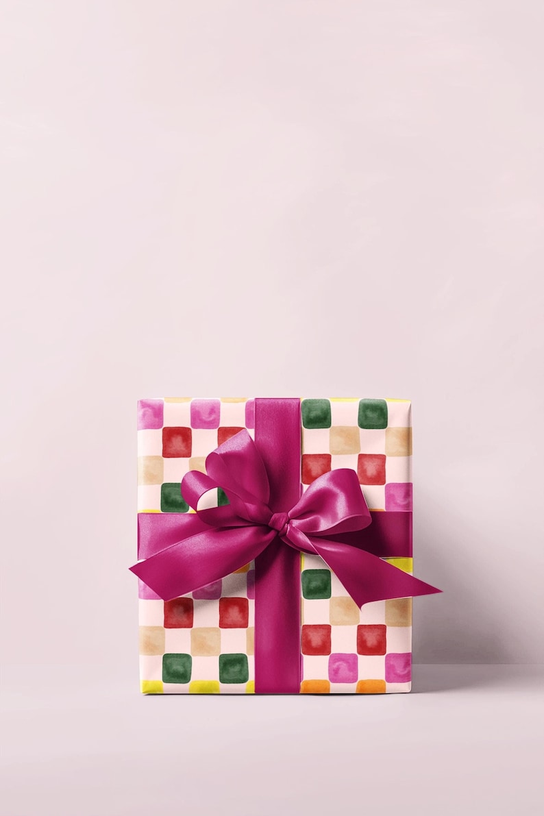 K&ouml;nnte beinhalten: Eine Geschenkbox, verpackt in buntes kariertes Papier mit einem rosa Satinband, das zu einer Schleife gebunden ist.