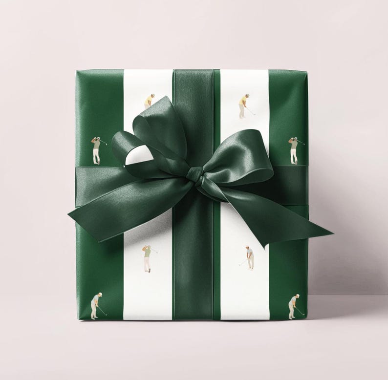 May include: Wrapped gift with green and white striped paper featuring miniature golfers. A dark green satin ribbon and bow are tied around the package. The gift wrap has a golf theme.