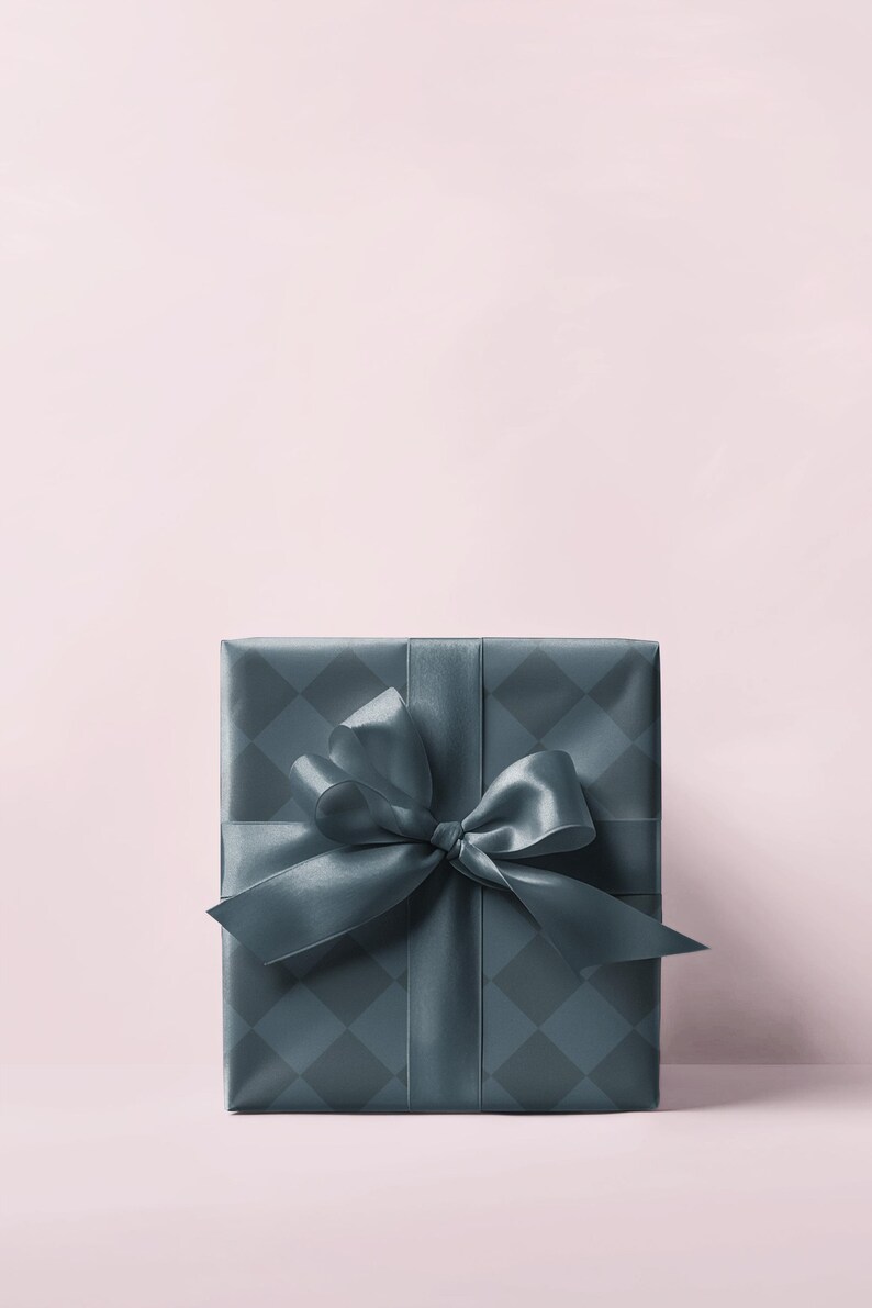 May include: A square gift box wrapped in teal paper with a diamond pattern. A matching teal satin ribbon is tied in a large bow on top. The background is a soft pink.