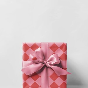 May include: A wrapped gift box with a pink satin ribbon and bow. The wrapping paper has a repeating pattern of red and pink diamonds. The gift is presented on a white background.