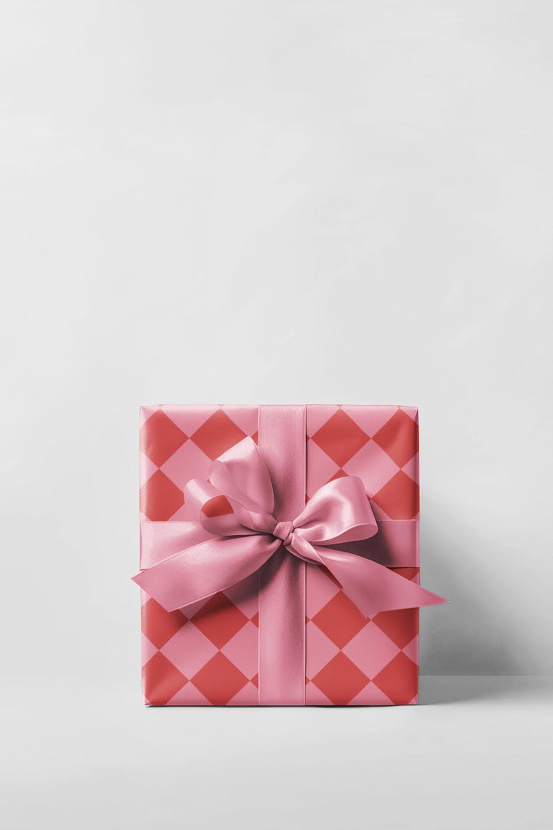 May include: A wrapped gift box with a pink satin ribbon and bow. The wrapping paper has a repeating pattern of red and pink diamonds. The gift is presented on a white background.