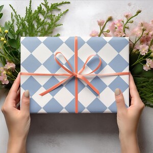 K&ouml;nnte beinhalten: Eine Geschenkbox, verpackt in blau-wei&szlig; kariertes Papier mit einem korallenfarbenen Band, das zu einer Schleife gebunden ist.