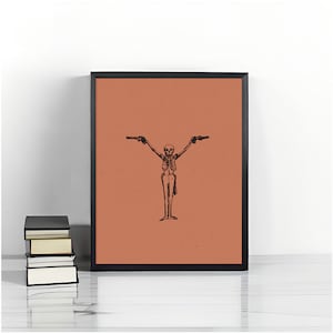 May include: A black and white illustration of a skeleton holding two pistols, printed on a peach-colored background. The illustration is framed in a black frame.