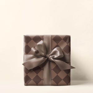 Op de afbeelding: Een bruine cadeaudoos met een bruin en wit geruit patroon en een bruin satijnen lint gebonden in een strik.