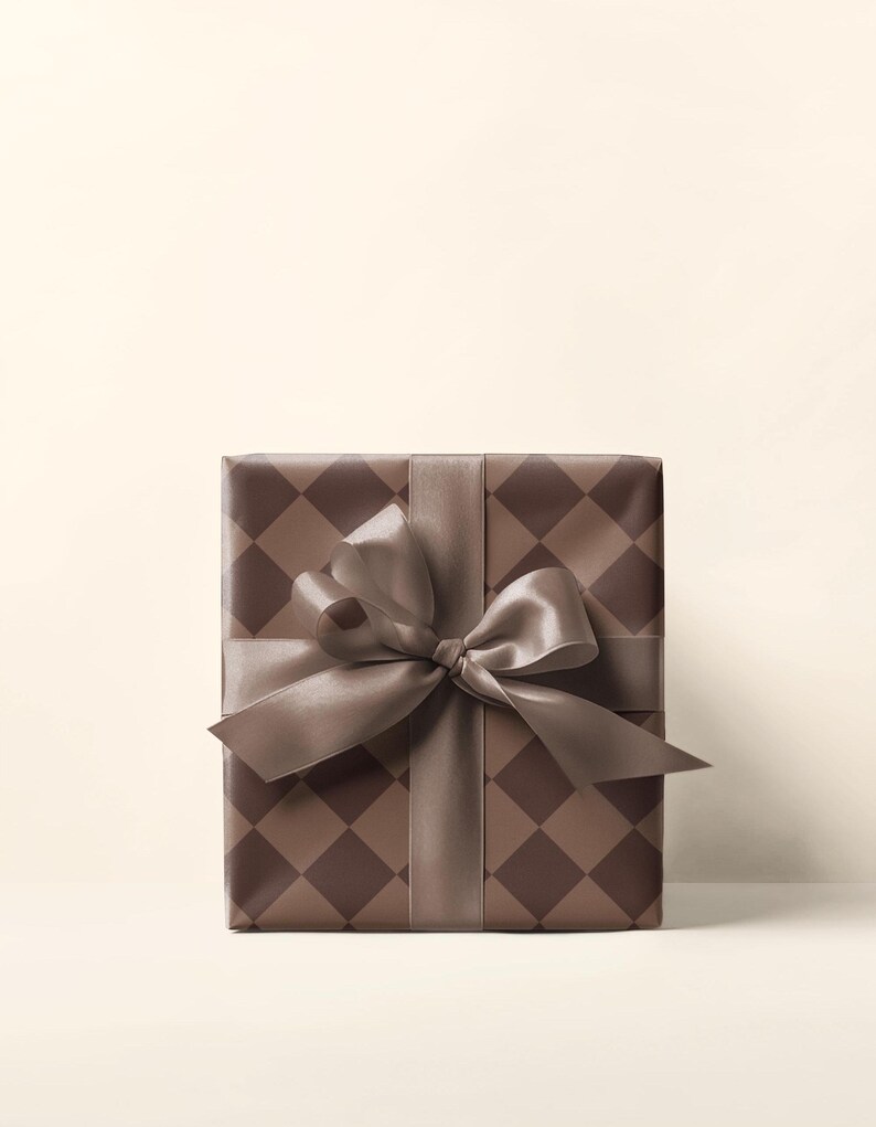 Op de afbeelding: Een bruine cadeaudoos met een bruin en wit geruit patroon en een bruin satijnen lint gebonden in een strik.