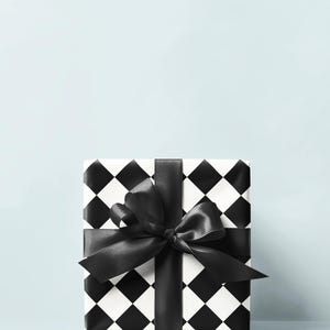 May include: A square gift box wrapped in black and white checkered paper. A wide black satin ribbon is tied around the box and forms a large bow on top. The background is a solid light blue.