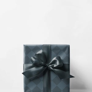 May include: A wrapped gift box with a dark teal diamond pattern and a matching satin ribbon and bow. The gift is centered on a white background, creating a clean and elegant presentation. The bow is large and decorative.