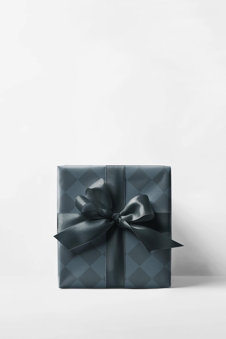 May include: A wrapped gift box with a dark teal diamond pattern and a matching satin ribbon and bow. The gift is centered on a white background, creating a clean and elegant presentation. The bow is large and decorative.