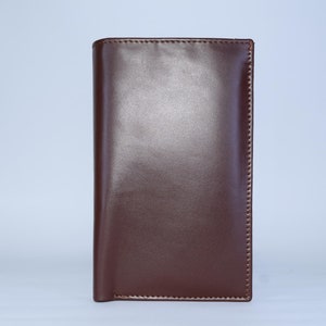 May include: A brown leather wallet with a smooth finish and stitched edges.