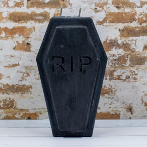 May include: A black coffin-shaped candle holder with the word "RIP" carved into the front.