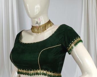 May include: A dark green velvet blouse with gold trim and green bead embellishments. The blouse has a scoop neckline and short sleeves.