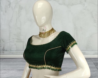 May include: A dark green velvet blouse with gold trim and green bead embellishments. The blouse has a scoop neckline and short sleeves.