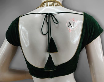 May include: A dark green velvet blouse with gold trim and a tie back. The blouse has short sleeves and a deep V-neck.