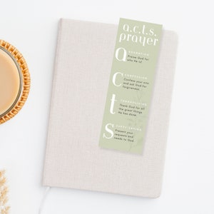 pastel green acts prayer bookmark on top of a journal