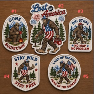 May include: Set of five embroidered patches featuring Bigfoot in various patriotic poses. Designs include text like "Gone Squatchin'", "Lost in America", "Big Steps", "Stay Wild", and "Land of the Free". Each patch has a unique shape and color scheme.