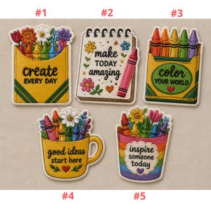 Peut inclure: Cinq écussons brodés avec des motifs colorés. Chaque écusson présente des crayons, des fleurs et des textes motivants comme "create every day" et "make today amazing". Les écussons sont de formes variées, dont une boîte de crayons et une tasse à café.