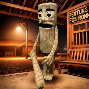 Op de afbeelding: Een grillig, antropomorf boomachtig figuur met een houten textuur, grote ogen en een brede mond. Het houdt een houten knuppel vast en staat voor een houten gebouw met de tekst "PENTUNG FOS RONN". De scène wordt verlicht door een straatlantaarn.