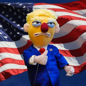 Könnte beinhalten: Eine Marionette mit gelben Haaren, einer roten Nase und einem blauen Anzug, die einen Daumen hoch zeigt. Die Marionette steht vor einer wehenden amerikanischen Flagge mit roten und weißen Streifen und weißen Sternen auf blauem Hintergrund.