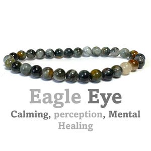 May include: A bracelet made of green, brown, and grey gemstone beads. The beads are round and have a smooth, polished finish. The bracelet is called "Eagle Eye" and is said to promote calming, perception, and mental healing.