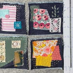 May include: Four small, square fabric patches with denim borders. Each patch features a unique design, including floral prints, lace, and decorative stitching. The patches are approximately 5 cm square, ideal for crafting or quilting projects.