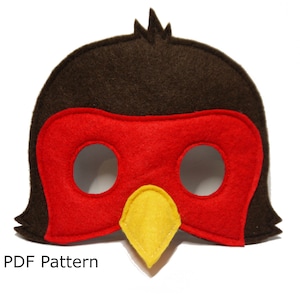 May include: A handmade felt bird mask in brown, red, and yellow. The mask features a red eye area, a yellow beak, and brown feathers. The text "PDF Pattern" is at the bottom.