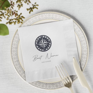 Puede incluir: Servilleta de papel blanca con un diseño de brújula y el texto "Boat Name LOCATION".