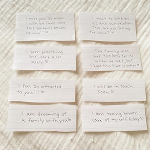Op de afbeelding: Acht handgeschreven briefjes op gelinieerd papier met korte berichten zoals "Ik mis je zo erg" en "Ik voel me zo aangetrokken tot je!!!". De briefjes zijn gerangschikt op een licht oppervlak.