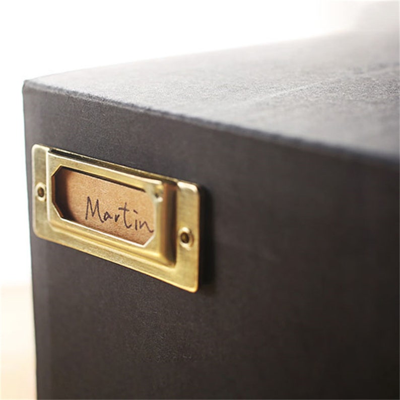 May include: A black box with a brass label holder. The label holder has a brown paper label with the word "Martin" written on it.