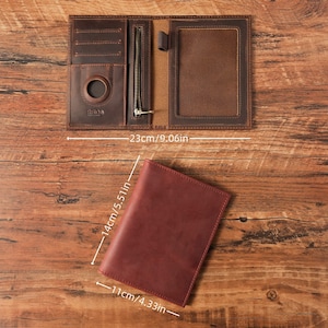 May include: A brown leather passport holder measuring 9.06 inches wide when open, with a closed height of 5.51 inches and width of 4.33 inches. The interior features card slots, a circular cutout, a zippered pocket, and a clear ID window.