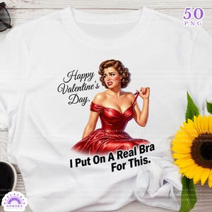 May include: White t-shirt with a retro illustration of a woman in a red dress, with the text "Happy Valentine's Day" and "I Put On A Real Bra For This.". The design includes a bouquet of sunflowers.