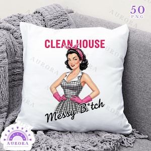May include: White square pillow with a retro illustration of a woman in a checkered dress, pink gloves, and a headband. Text reads "CLEAN HOUSE" in pink and "Messy B*tch" in black. The pillow is on a gray couch.