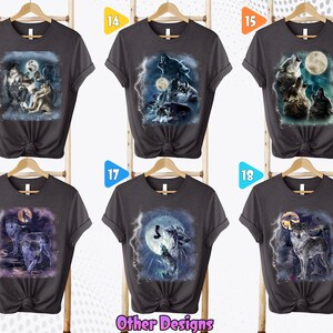 K&ouml;nnte beinhalten: Sechs graue T-Shirts mit verschiedenen Wolf-Designs, die darauf gedruckt sind. Die Designs zeigen W&ouml;lfe, die zum Mond heulen, wobei einige Designs Blitze und andere Naturelemente enthalten. Die Shirts werden alle auf Kleiderb&uuml;geln pr&auml;sentiert, wobei die Nummern 13, 14, 15, 16, 17 und 18 oben auf jedem Shirt sichtbar sind.