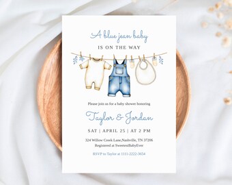 May include: Baby shower invitation with the text "A blue jean baby is on the way." The invitation features illustrations of baby clothes hanging on a clothesline, including a onesie, overalls, and a bib. The invitation is for Taylor & Jordan.