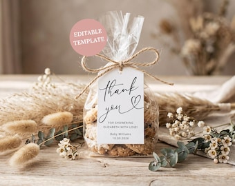 May include: A clear plastic treat bag filled with cookies, tied with brown twine and a white rectangular tag. The tag features black cursive text reading thank you, FOR SHOWERING ELIZABETH WITH LOVE!, Baby WILLIAMS, and 10.09.2026, with a pink EDITABLE TEMPLATE circle.