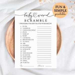 May include: A black and white baby shower word scramble game with the text "baby word scramble" and "Fun & Simple printable". The game includes a list of scrambled words related to babies. The game is on a white paper.