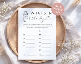 May include: A white rectangular game card with black text and a line drawing of a shopping bag with a heart. The card reads WHAT'S IN THE BAG and includes instructions for a baby shower game with blank lines for guesses next to the letters B A B Y and S H O W E R.