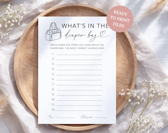 May include: A white paper game card titled WHAT'S IN THE diaper bag with a line drawing of a diaper bag, a numbered list from 1 to 12, and spaces for Name and Total points. A pink circular badge in the corner reads READY TO PRINT FILES.