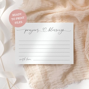 May include: A white rectangular card featuring the black text prayers blessings with a small heart symbol in the centre. The card includes five horizontal lines for writing and the text with love followed by a line at the bottom left corner.