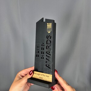 May include: Black wooden award with the text "FHA Beer Awards" and "Pale Lager of the Year 2024" on a wooden base.