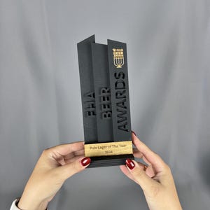 May include: Black and gold award trophy with the text "FHA Beer Awards" and "Pale Lager of The Year 2024".