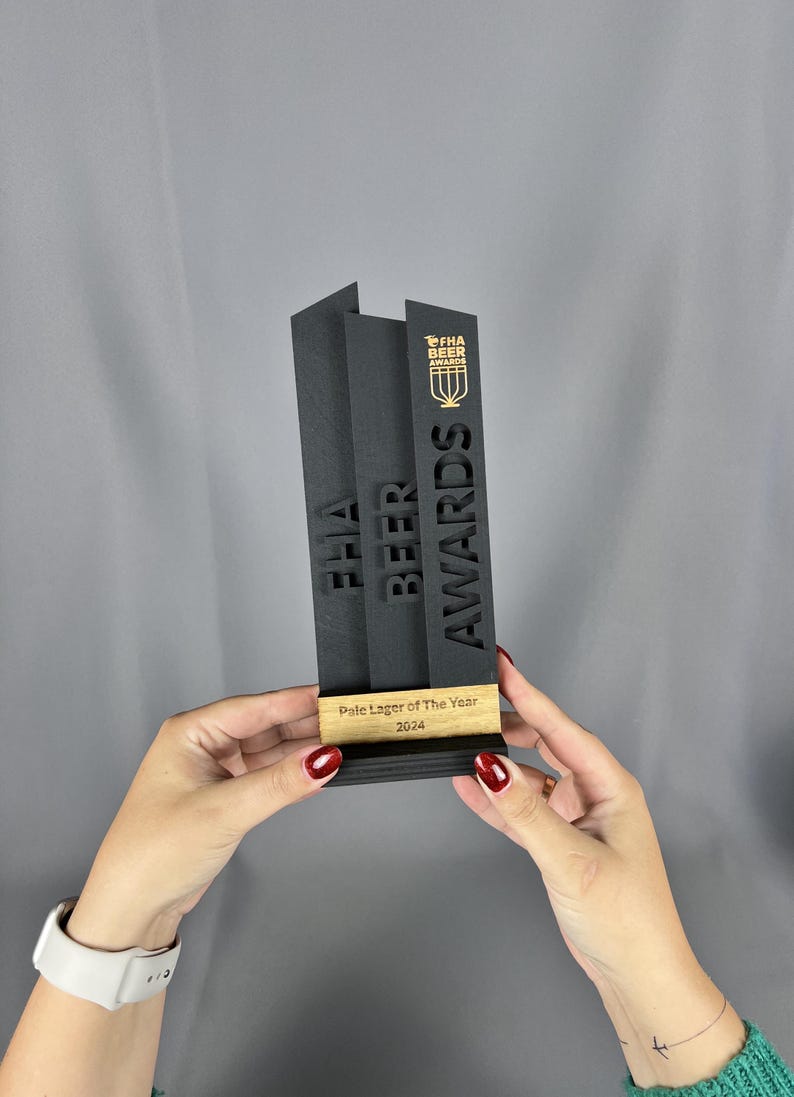 May include: Black and gold award trophy with the text "FHA Beer Awards" and "Pale Lager of The Year 2024".