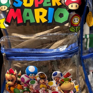May include: A clear blue backpack with a zipper closure. The front of the backpack has a large "SUPER MARIO" graphic with various characters from the video game series.