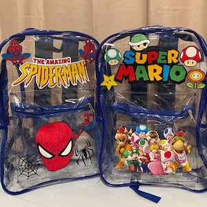 Op de afbeelding: Twee transparante blauwe rugzakken met kleurrijke cartoonfigurenontwerpen. Eén rugzak heeft Spiderman met de tekst "The Amazing Spiderman". De andere rugzak heeft Super Mario met de tekst "Super Mario".
