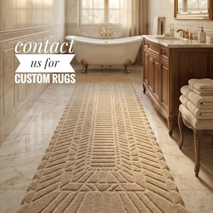 Könnte beinhalten: Ein beigefarbener rechteckiger Teppich mit geometrischem Muster befindet sich in einem Badezimmer. Der Teppich hat einen gewellten Rand und ist vor einer Badewanne mit Löwenfüßen platziert. Der Text links lautet "Kontaktieren Sie uns für individuelle Teppiche."