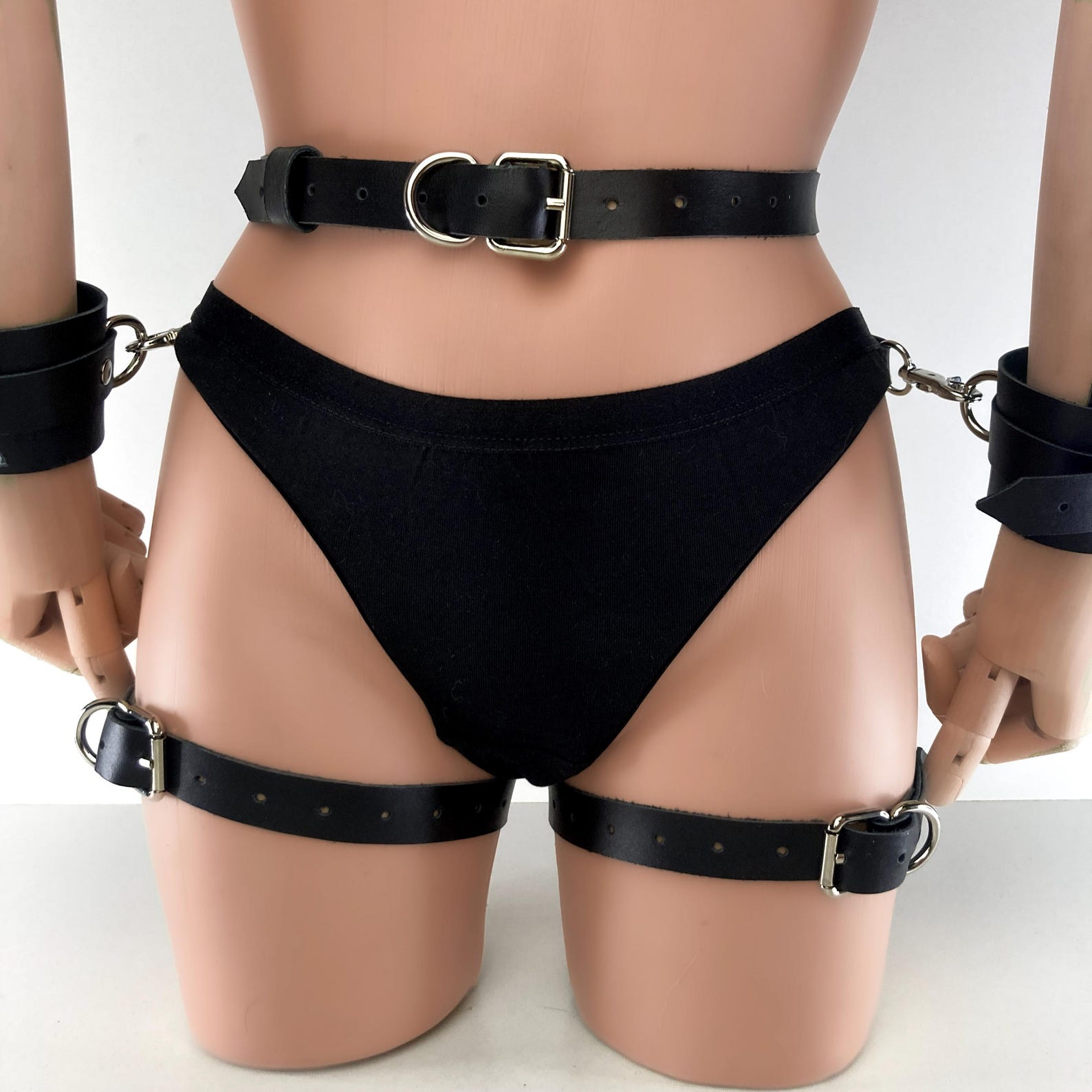 Cowhide leather BDSM harness with adjustable straps, thigh cuffs, and wrist restraints for bondage wear.