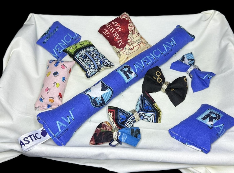 Peut inclure: Un ensemble de jouets pour chat sur le th&egrave;me d'Harry Potter, de couleur bleu et blanc. Les jouets comprennent un long jouet &agrave; chat en catnip bleu avec l'embl&egrave;me de la maison Serdaigle et les mots "Wit Learning Wisdom", un plus petit jouet &agrave; chat en catnip bleu avec l'embl&egrave;me de la maison Serdaigle, un jouet &agrave; chat en catnip rose et blanc &agrave; pois, un jouet &agrave; chat en catnip bleu et blanc avec l'embl&egrave;me de Poudlard, un jouet &agrave; chat en catnip bleu et blanc avec la carte du Maraudeur, et trois n&oelig;uds papillon bleu et blanc avec l'embl&egrave;me de la maison Serdaigle.