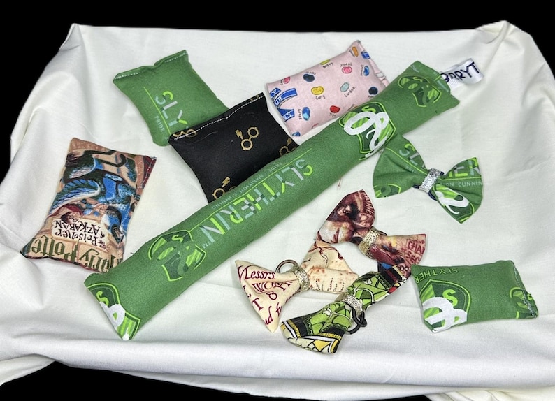 Peut inclure: Un ensemble de neuf jouets pour chat en tissu de couleur verte, noire et cr&egrave;me avec diff&eacute;rents motifs sur le th&egrave;me d'Harry Potter. Les jouets comprennent un long jouet vert avec les mots "Slytherin" imprim&eacute;s dessus, un jouet noir avec les mots "Slytherin" imprim&eacute;s dessus et un jouet cr&egrave;me avec les mots "Azakaban Prisoner" imprim&eacute;s dessus.