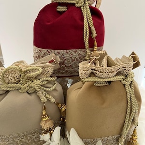 May include: Three velvet drawstring bags in burgundy, tan, and beige. Each bag features a decorative lace trim, gold rope drawstring, and tassel accents. The bags are likely for gifts or storage.