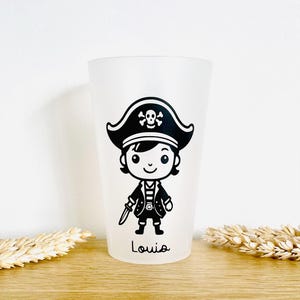 Peut inclure: Un verre givré avec un dessin de pirate de dessin animé en noir et blanc. Le pirate porte un chapeau avec une tête de mort et des os croisés, une veste et tient un couteau. Le nom "Louisa" est imprimé au bas du verre.
