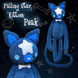 May include: A dark blue plush cat toy with a white star on its forehead, light blue button eyes, a white bone-shaped collar, and long limbs. The text "Falling Star Kitties: Peak" is visible alongside white line drawings of a skull and stars.